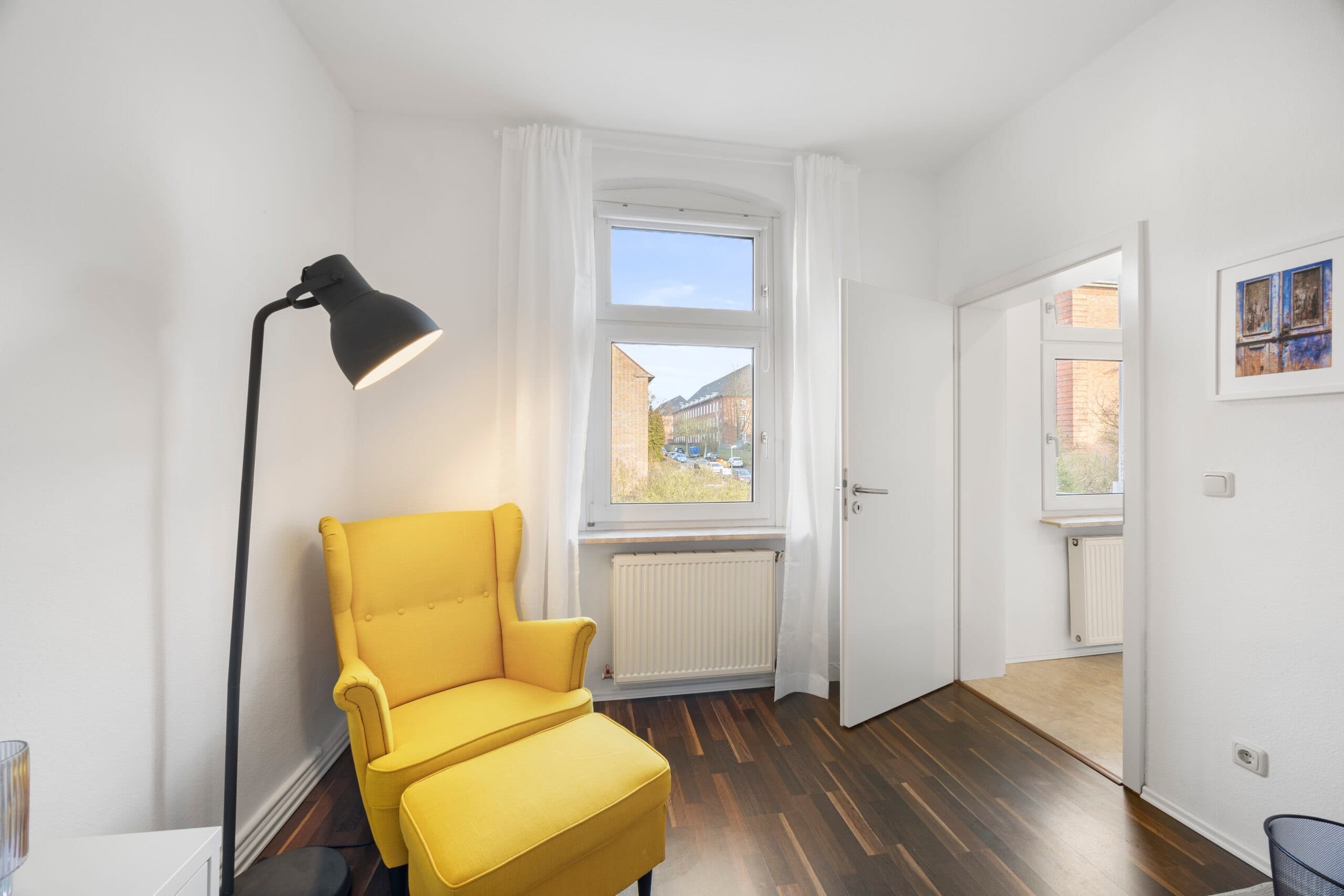 Höhenverstellbarer Schreibtisch vor dem Fenster mit Vorhang