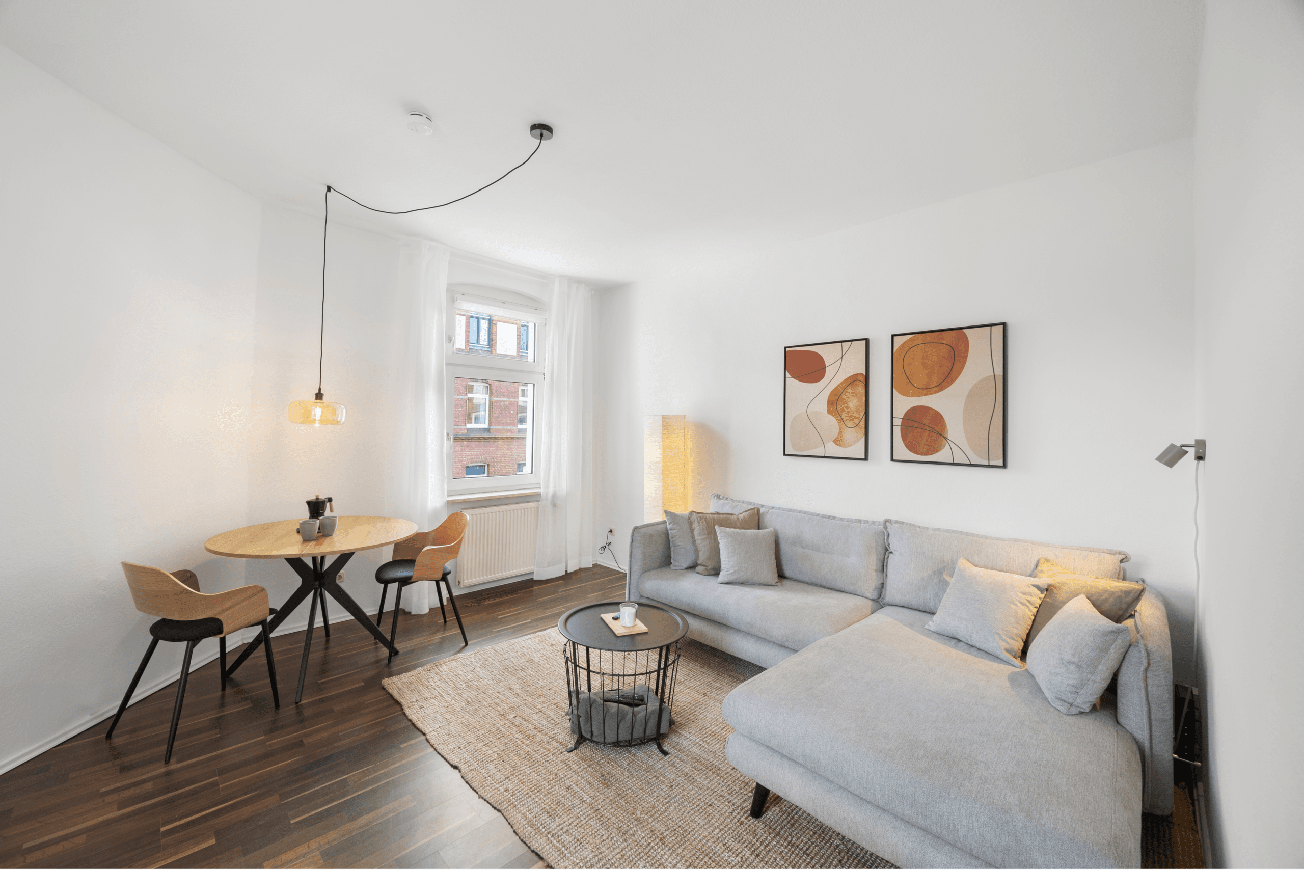 Wohnbereich mit hellem Sofa, Teppich und Fenster zur Straße